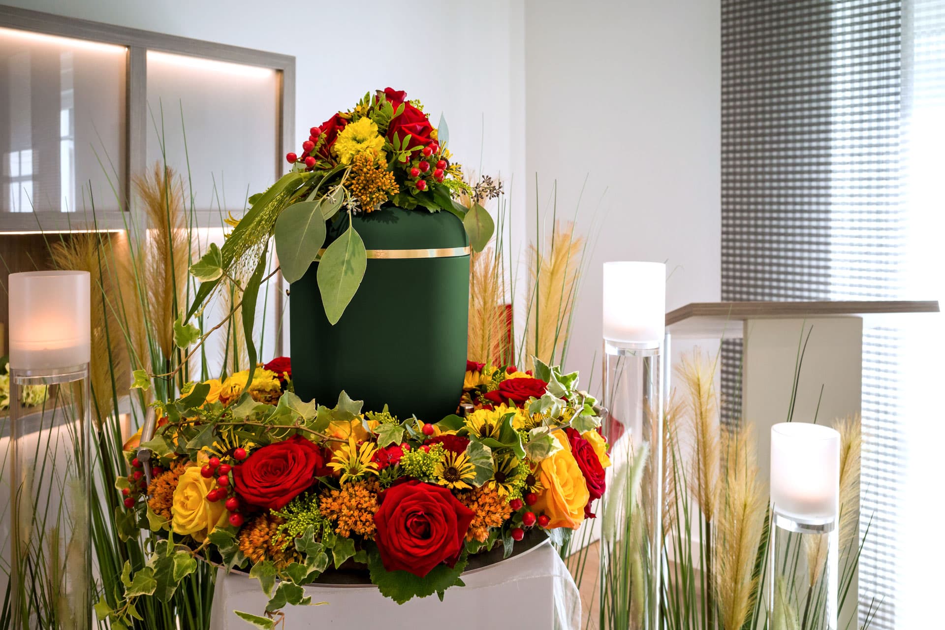 Grüne Urne mit Blumenschmuck bei einer Feuerbestattung in Bietigheim-Bissingen, Kuhn Bestattungen.