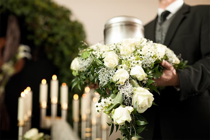 Urne mit weißem Blumenarrangement bei einer Trauerfeier auf dem Friedhof Oßweil, organisiert von Kuhn Bestattungen.