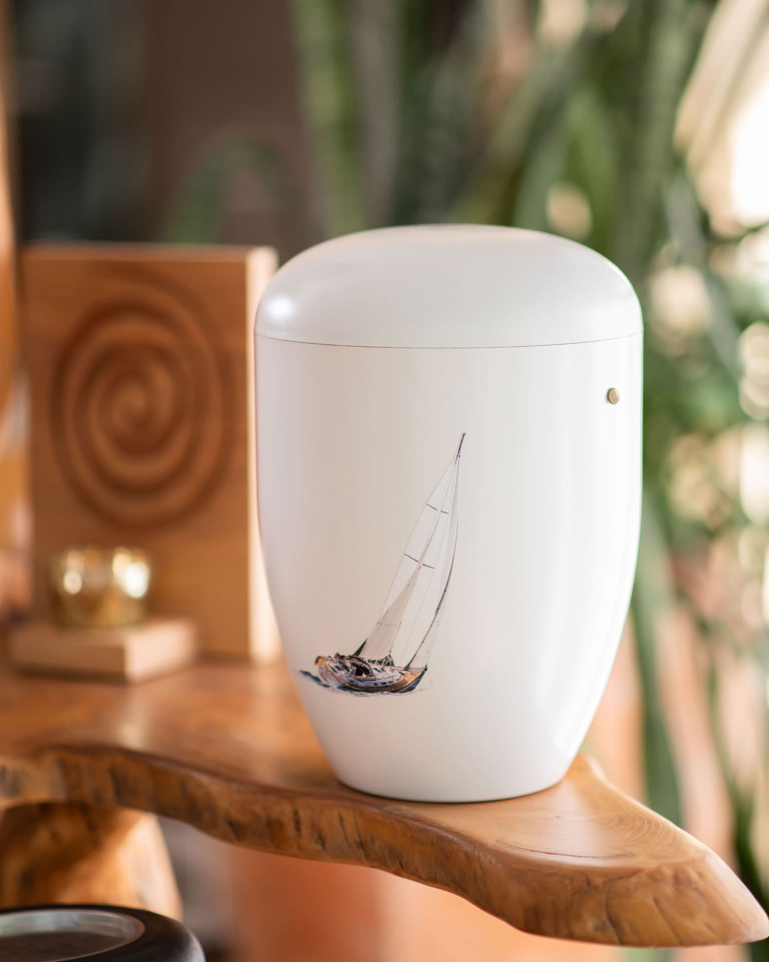 Weiße Urne mit einem handgemalten Segelboot-Motiv, vorbereitet für eine Seebestattung. Naturverbundene und würdevolle Abschiednahme auf See durch Kuhn Bestattungen in Asperg.