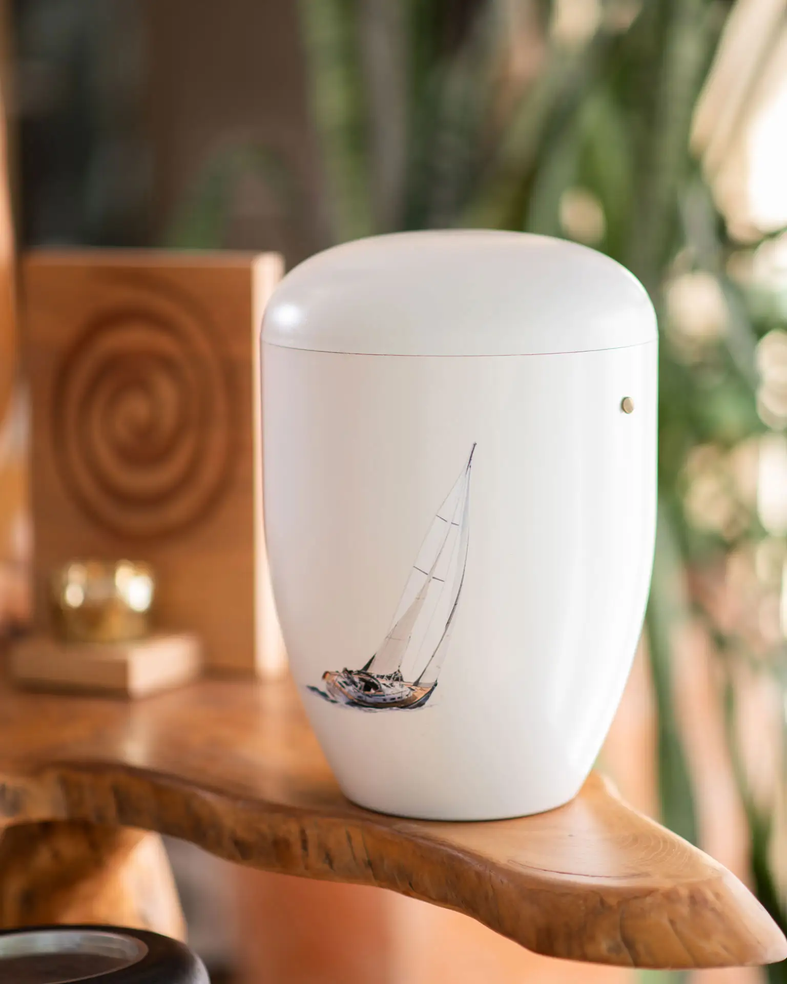 Seebestattung – Würdevolle Beisetzung auf See bei Kuhn Bestattungen Weiße Urne mit einem handgemalten Segelboot-Motiv, vorbereitet für eine Seebestattung. Naturverbundene und würdevolle Abschiednahme auf See durch Kuhn Bestattungen in Asperg.