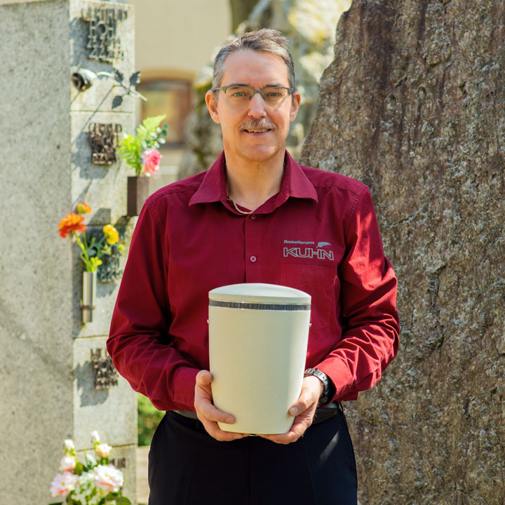 Bestattungsvorsorge und Begleitung im Trauerfall durch Michael Großhaupt Michael Großhaupt von Kuhn Bestattungen mit Urne am Friedhof Asperg